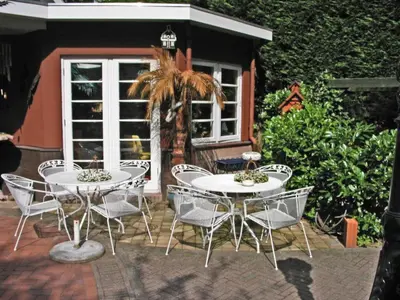 a patio with two tables and chairs and a palm tree at Villa Prinsenhof # Zeventien in Bergen