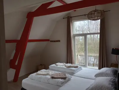 two beds in a room with a large window at Het Dijkstuk in Noordwijkerhout