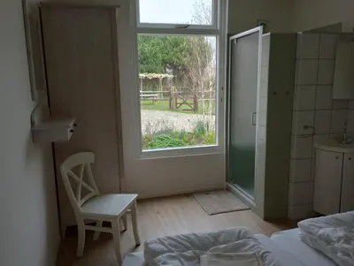a bedroom with a bed and a window and a chair at Het Dijkstuk in Noordwijkerhout