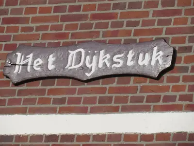 a sign on the side of a brick wall at Het Dijkstuk in Noordwijkerhout