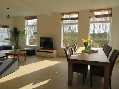 a living room with a table and chairs and a television at Het Dijkstuk in Noordwijkerhout