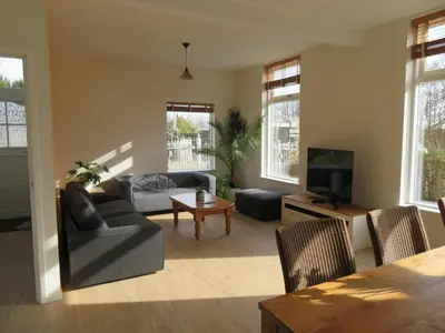 a living room with a couch and a tv at Het Dijkstuk in Noordwijkerhout