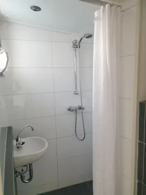 a bathroom with a shower curtain and a sink at Little Lodge Noordwijk aan Zee in Noordwijk