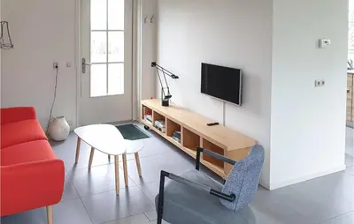 a living room with a television and a red couch at Lovely Home In Wijdenes With Wifi in Wijdenes