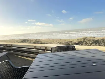 a table and chairs on the beach with the ocean at Appartementen met uniek zeezicht in Egmond aan Zee