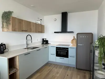 a kitchen with white cabinets and a refrigerator at Appartementen met uniek zeezicht in Egmond aan Zee
