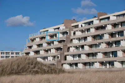 an apartment building with a blue sign on it at Appartementen met uniek zeezicht in Egmond aan Zee