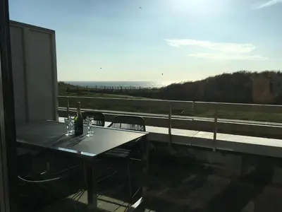 a table and chairs on a balcony with a view of the ocean at Appartementen met uniek zeezicht in Egmond aan Zee