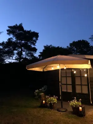 a lit up umbrella in a yard at night at Schoorl Seasons Garden House 2026 in Schoorl