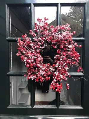a person in a window with a wreath of red flowers at Schoorl Seasons Garden House 2026 in Schoorl