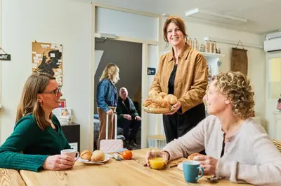 two women sitting at a table with a woman holding a basket at B&B Hartje Spakenburg in Spakenburg