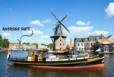 a boat in the water next to a windmill at RiverSide Suite - Haarlem City Centre in Haarlem