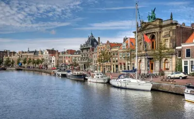 a group of boats are docked in a river with buildings at RiverSide Suite - Haarlem City Centre in Haarlem