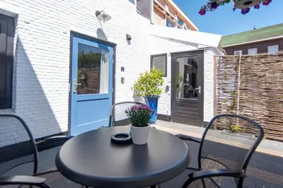 a table and chairs on a patio with a door at Zee & Zo in Zandvoort