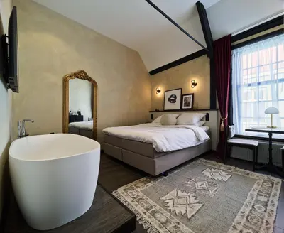 a bedroom with a large bed and a bath tub at Boutique Hotel & Restaurant Frenchie in Haarlem