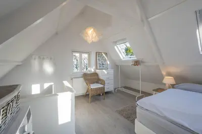 a white bedroom with a bed and a chair at Villa Bo Junior in Bergen