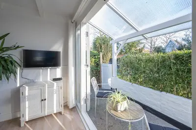 a room with a balcony with a table and a tv at Villa Bo Junior in Bergen