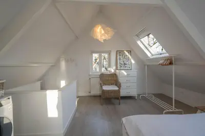 a attic room with a bed and a chair at Villa Bo Junior in Bergen
