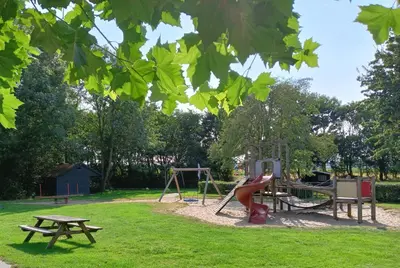 a park with a playground and a picnic table at Vakantiehuis Friedeburg in Warmenhuizen
