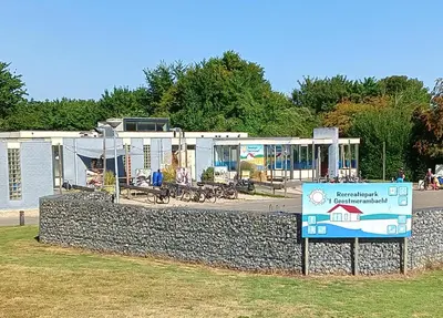 a sign in front of a building with a playground at Vakantiehuis Friedeburg in Warmenhuizen