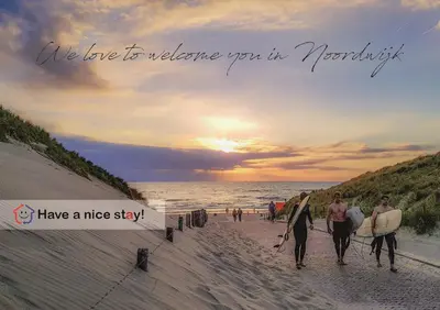 a group of people walking on the beach with surfboards at Have a nice stay! - Blue Beach House 350 meters from sea in Noordwijk aan Zee