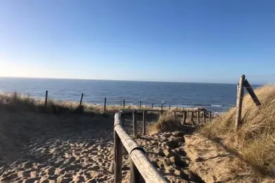a beach with a wooden fence and the ocean at Have a nice stay! - Blue Beach House 350 meters from sea in Noordwijk aan Zee