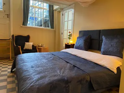 a bedroom with a large bed and a chair at Prinsengracht Museum Bed and Breakfast in Amsterdam
