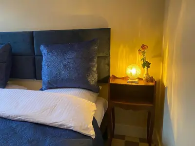 a bed with a blue headboard and a side table with a lamp at Prinsengracht Museum Bed and Breakfast in Amsterdam
