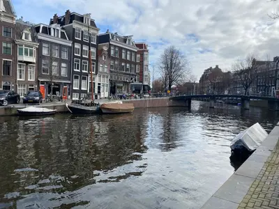 a river with boats in a city with buildings at Prinsengracht Museum Bed and Breakfast in Amsterdam