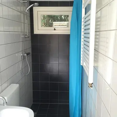 a bathroom with a blue shower curtain and a window at Chalet Bergen NH, Schoorl, Schoorldam in Warmenhuizen