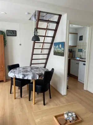 a dining room with a table and chairs and a staircase at Torensdoin in Egmond aan Zee