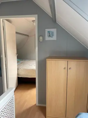 a bedroom with a bed and a wooden cabinet at Torensdoin in Egmond aan Zee