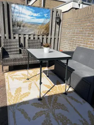 a table on a patio with a couch and a chair at Torensdoin in Egmond aan Zee