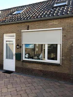 a window with a white awning on a brick building at Torensdoin in Egmond aan Zee