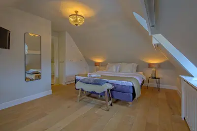 a bedroom with a large bed and a staircase at Grandcafé Boutique Hotel Eemland in Eemnes