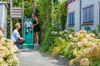a woman and a boy sitting on a green slide in a garden at Grandcafé Boutique Hotel Eemland in Eemnes