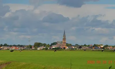 a green field with a church in the background at B&B De Kamer in Wervershoof