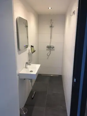 a white bathroom with a sink and a mirror at B&B De Kamer in Wervershoof