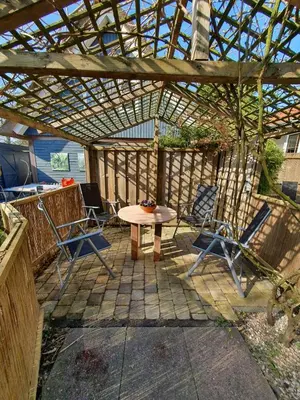 a patio with a table and chairs under a pergola at Appartement Schoorl in Schoorl