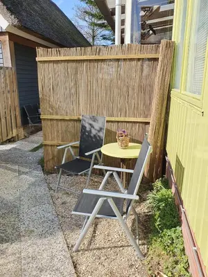 a table and two chairs next to a fence at Appartement Schoorl in Schoorl