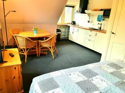 a room with a table and chairs and a kitchen at Appartement Schoorl in Schoorl