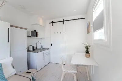 a small white kitchen with a white table and chairs at Studio Jadana in Zandvoort