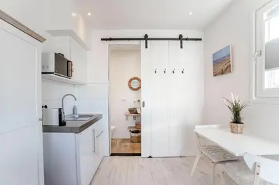 a white kitchen with a sink and a table at Studio Jadana in Zandvoort