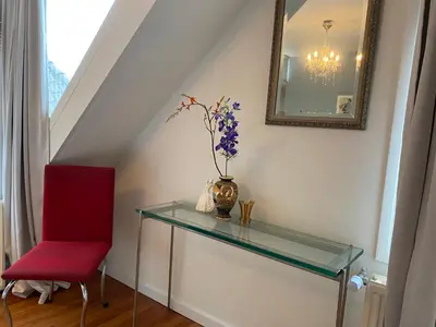 a glass table with a vase and a red chair at Park View Apartment in Amsterdam