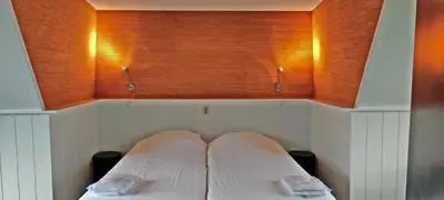 a bed in a room with two pillows on it at Hotelhuisje Warmenhuizen #A in Warmenhuizen