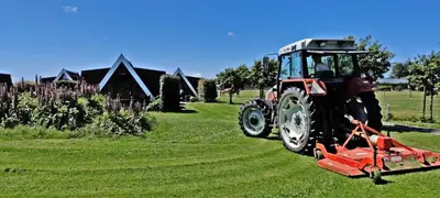 a tractor is parked on the grass in a field at Hotelhuisje Warmenhuizen #A in Warmenhuizen