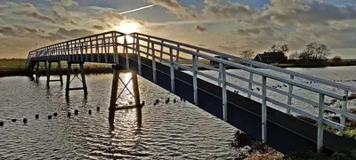 a bridge over a body of water with ducks on it at Hotelhuisje Warmenhuizen #A in Warmenhuizen