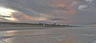 a view of a beach with a building in the distance at Hotelhuisje Warmenhuizen #A in Warmenhuizen