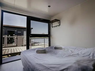 a bedroom with a bed and a large window at Holiday Home Havenlodge by Interhome in Uitgeest