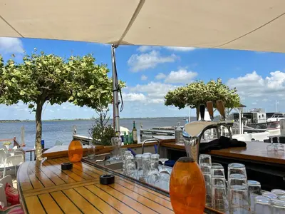 a table with glasses on it with a view of the water at Holiday Home Havenlodge by Interhome in Uitgeest